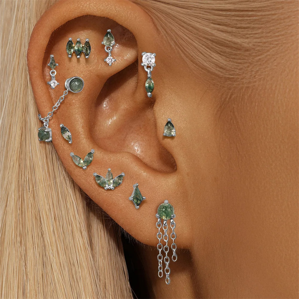 Close-up of an ear with multiple green gemstone earrings.