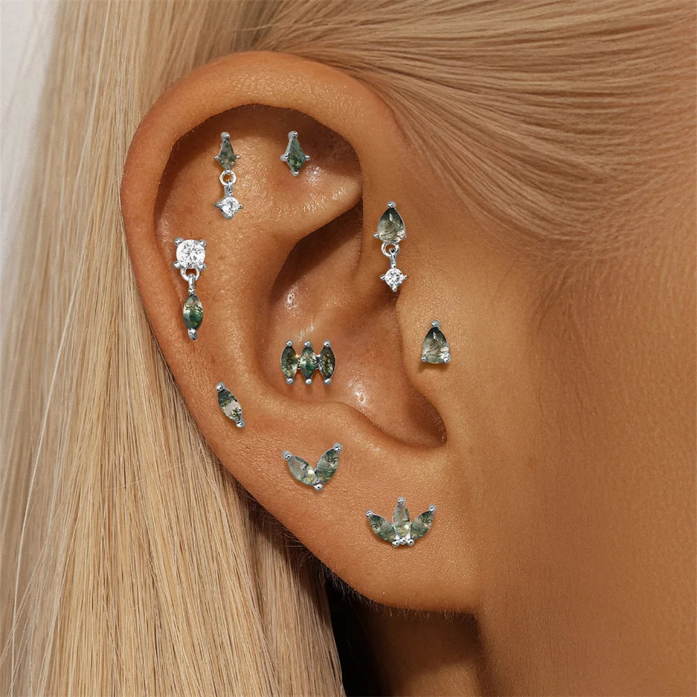 Close-up of an ear with multiple gemstone earrings.
