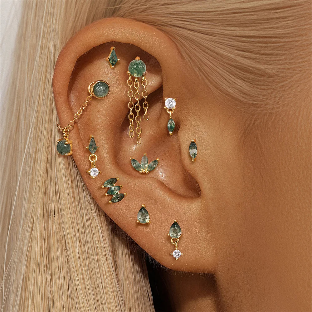 Close-up of an ear with multiple gold and gemstone earrings.