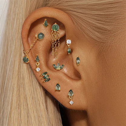 Close-up of an ear with multiple gold and gemstone earrings.